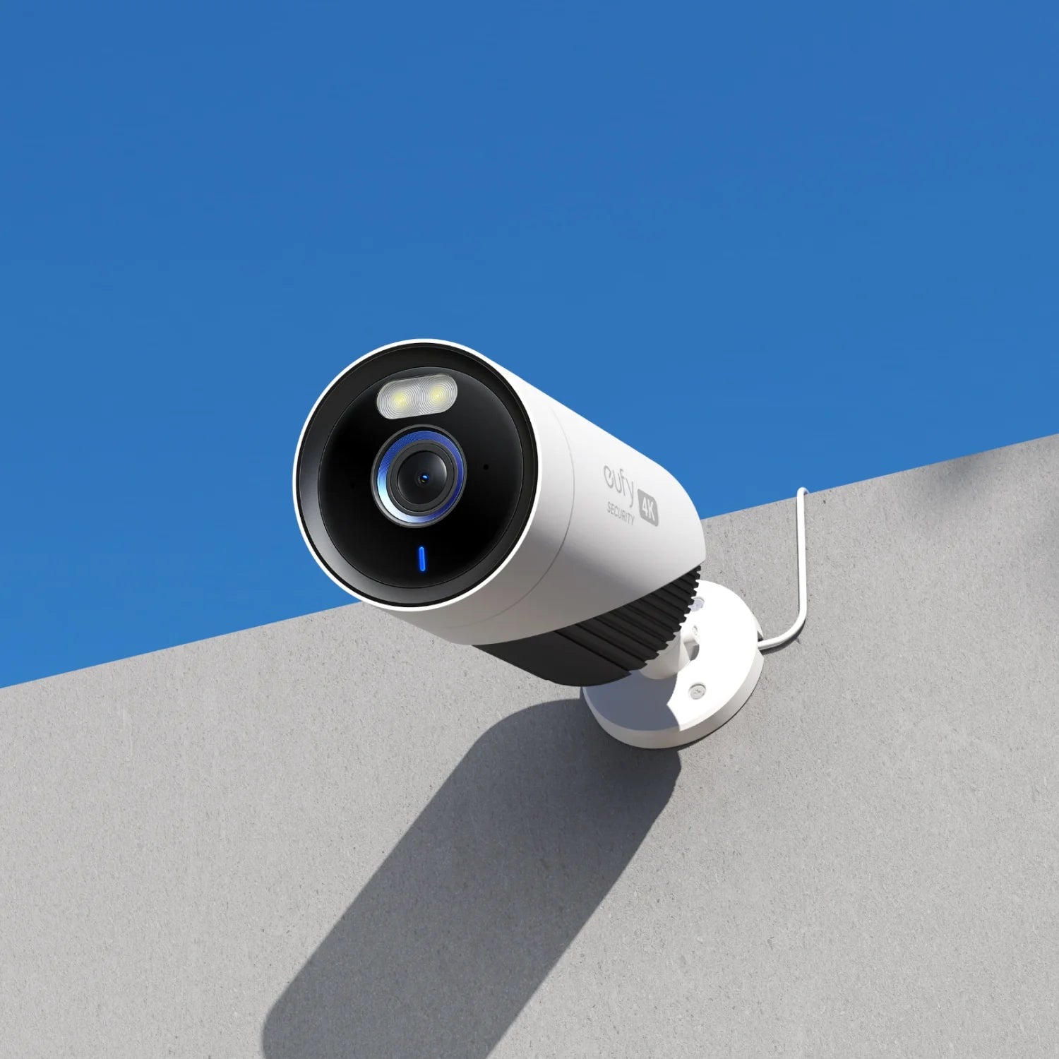 White security camera on a gray surface with a blue sky background