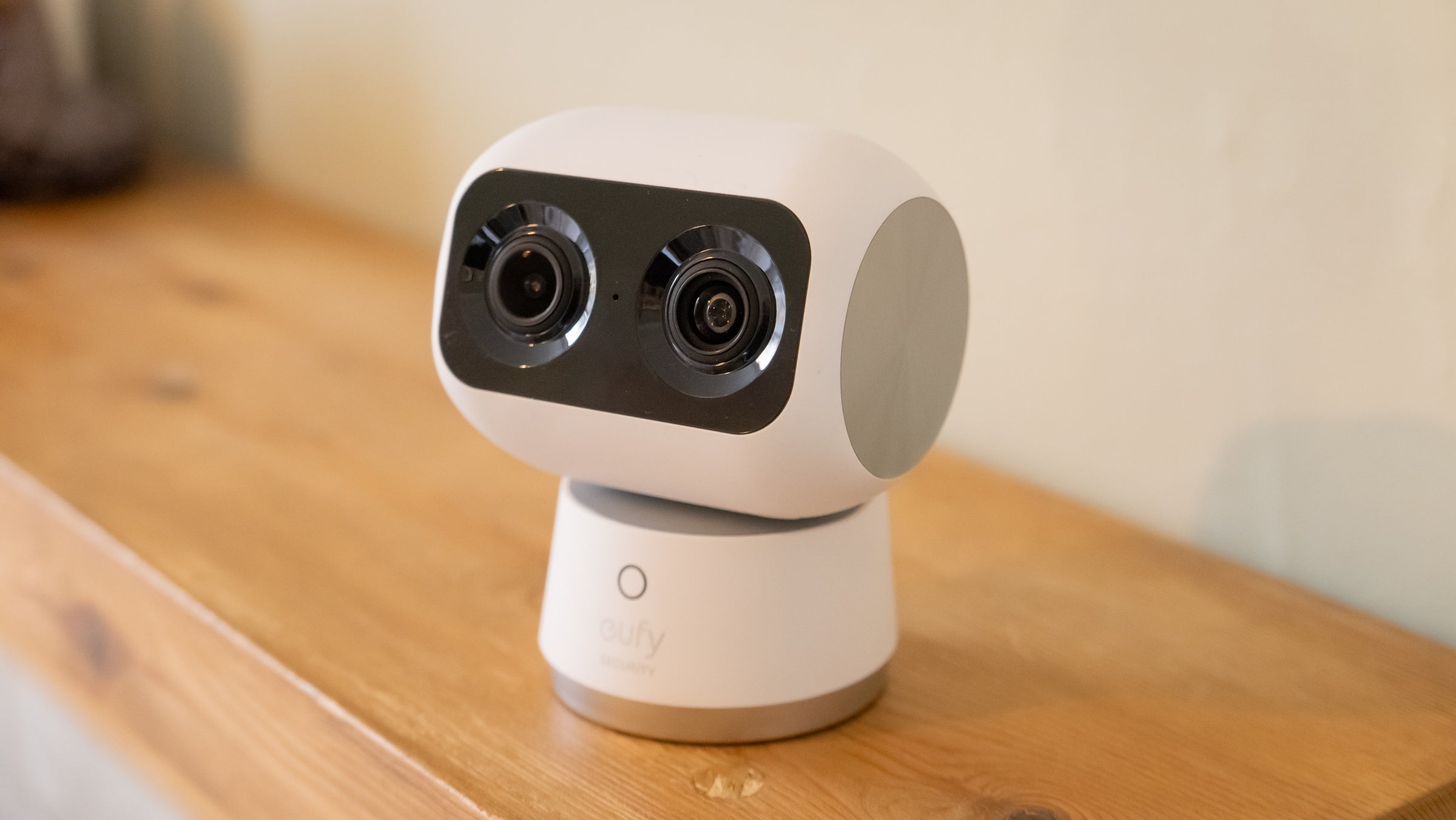 White robot-like device with camera lenses on a wooden surface
