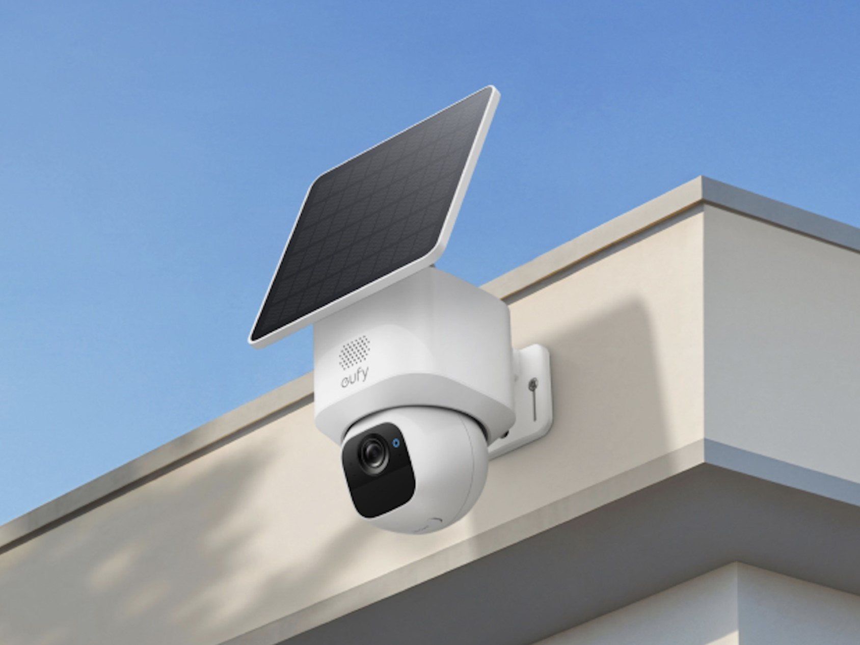 Security camera with solar panel on a roof against a clear blue sky
