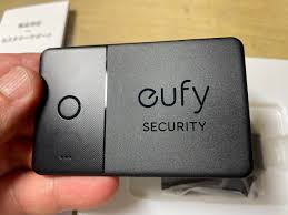 Black device with 'eufy Security' branding held in a hand on a wooden surface.