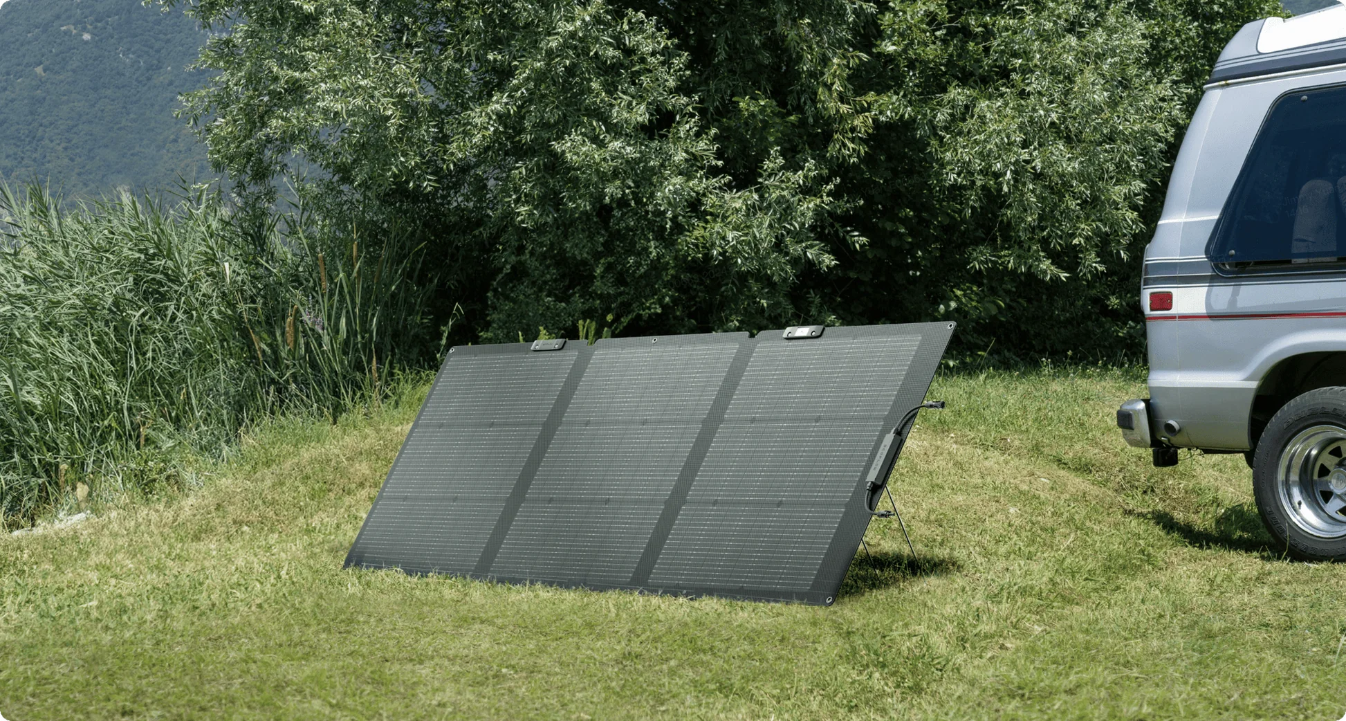 Solar panel on grass next to a van in a natural setting