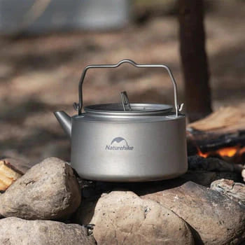 Camping kettle on a campfire with 'Natureshine' branding