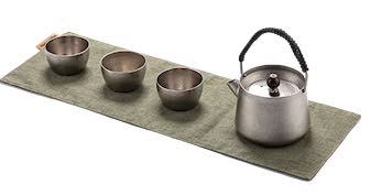 Tea set with a teapot and four cups on a green mat