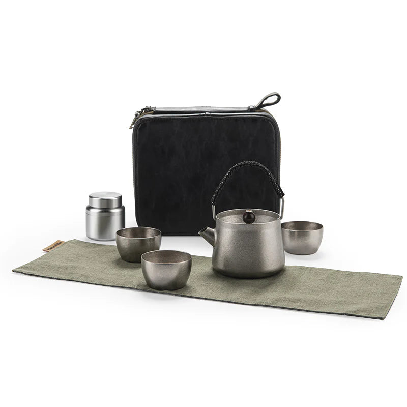 Tea set with teapot, cups, and thermos on a green mat with a black carrying case.