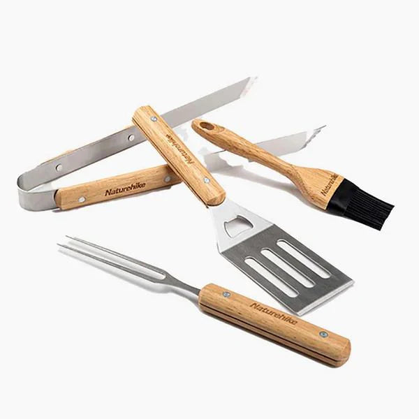 Set of four Natureshirr BBQ tools including a fork, spatula, skewer, and brush on a white background.