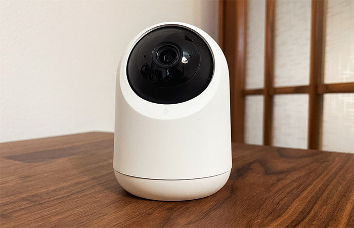 White security camera on a wooden surface with a neutral background